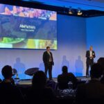 Presenters on stage in from of a screen at the the 13th annual AlixPartners Foodservice Growth Event, held at the QEII Centre in London