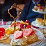 Close up of an afternoon tea stand containing cakes, strawberry scones and finger sandwiches