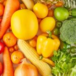 Close up of a variety of vegetable and fruit. The left of the shot is all red items and it merges to yellow in the middle and green on the right.